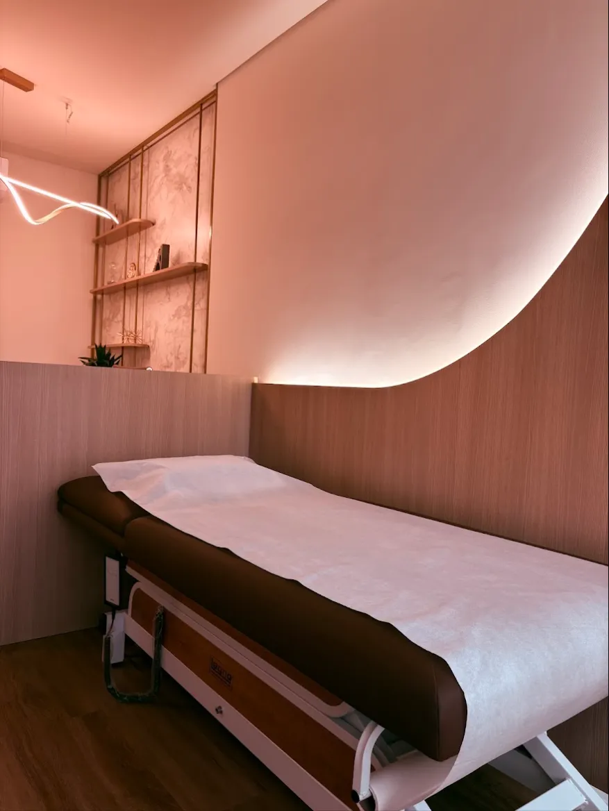 Sala de atendimento com maca e parede iluminada em curva